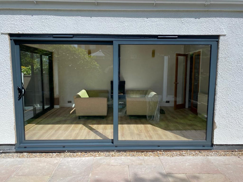 Modern sliding glass door leading to a living room with furniture.