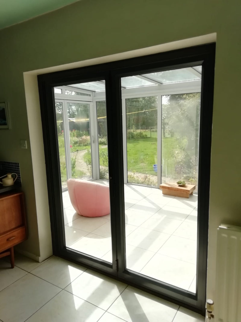 Sliding glass door leading to a garden view with a pink chair inside.