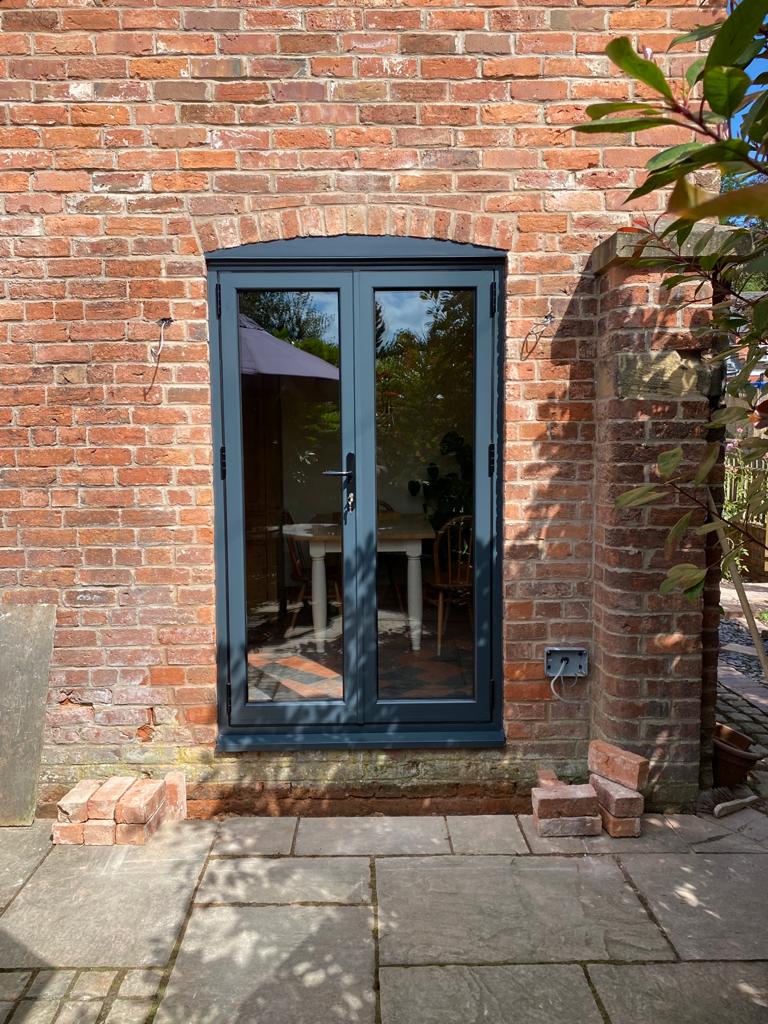 Blue French door on a brick wall with outdoor furniture visible