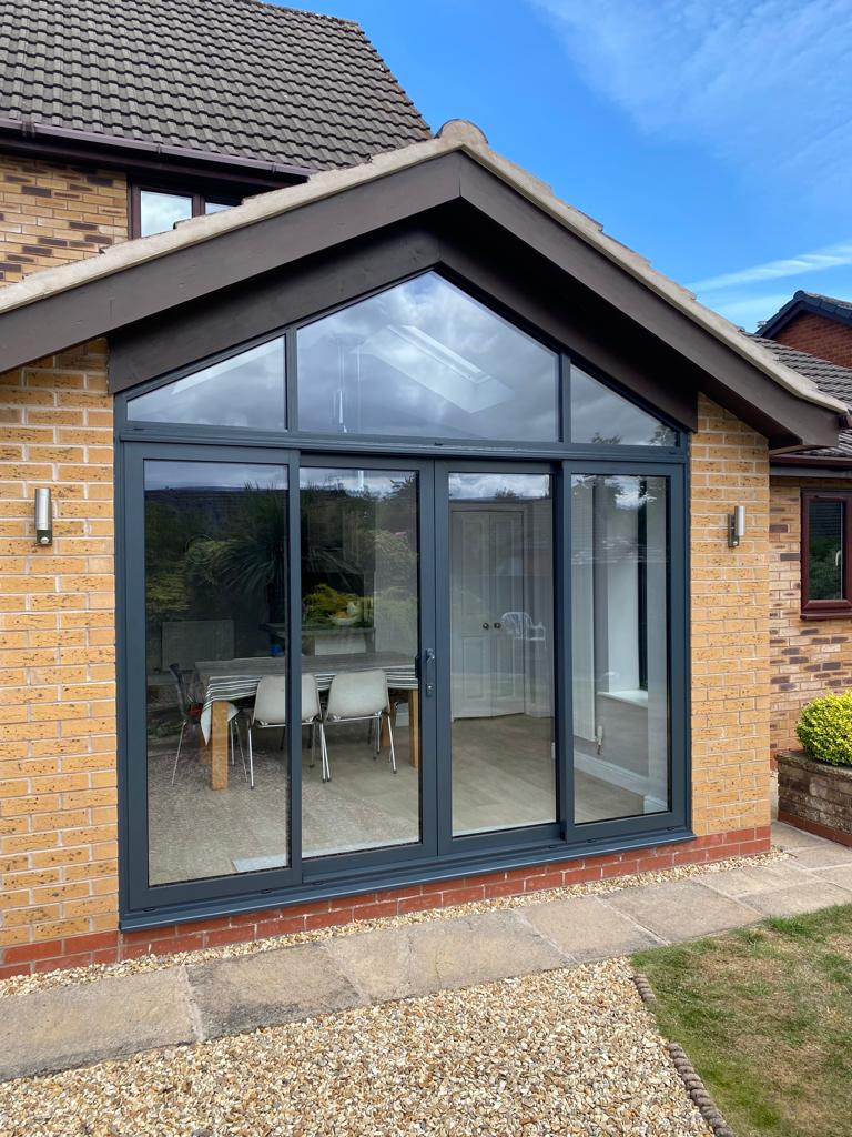 Modern extension with large glass doors and windows on a brick house.