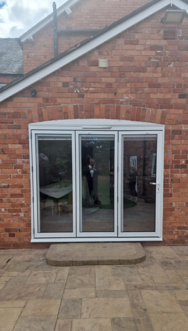 White patio door on a brick house with a paved patio area.