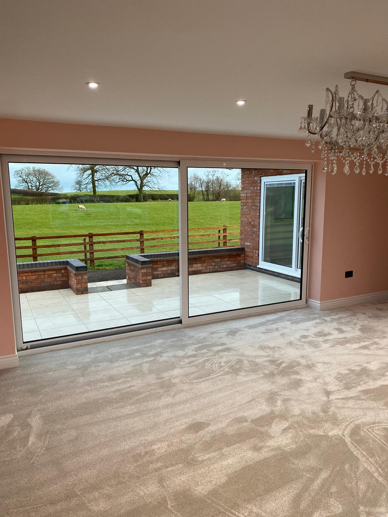 Living room with large sliding glass doors leading to a garden view, featuring a chandelier.