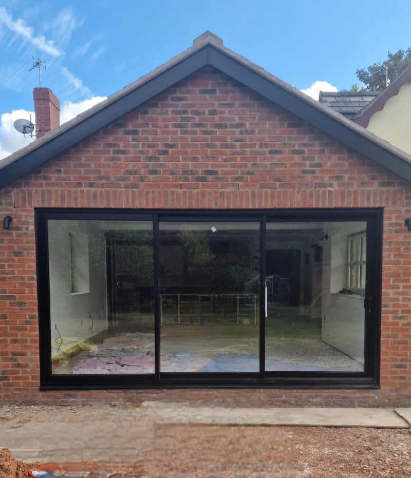 Brick house with a large black-framed glass door on a clear day