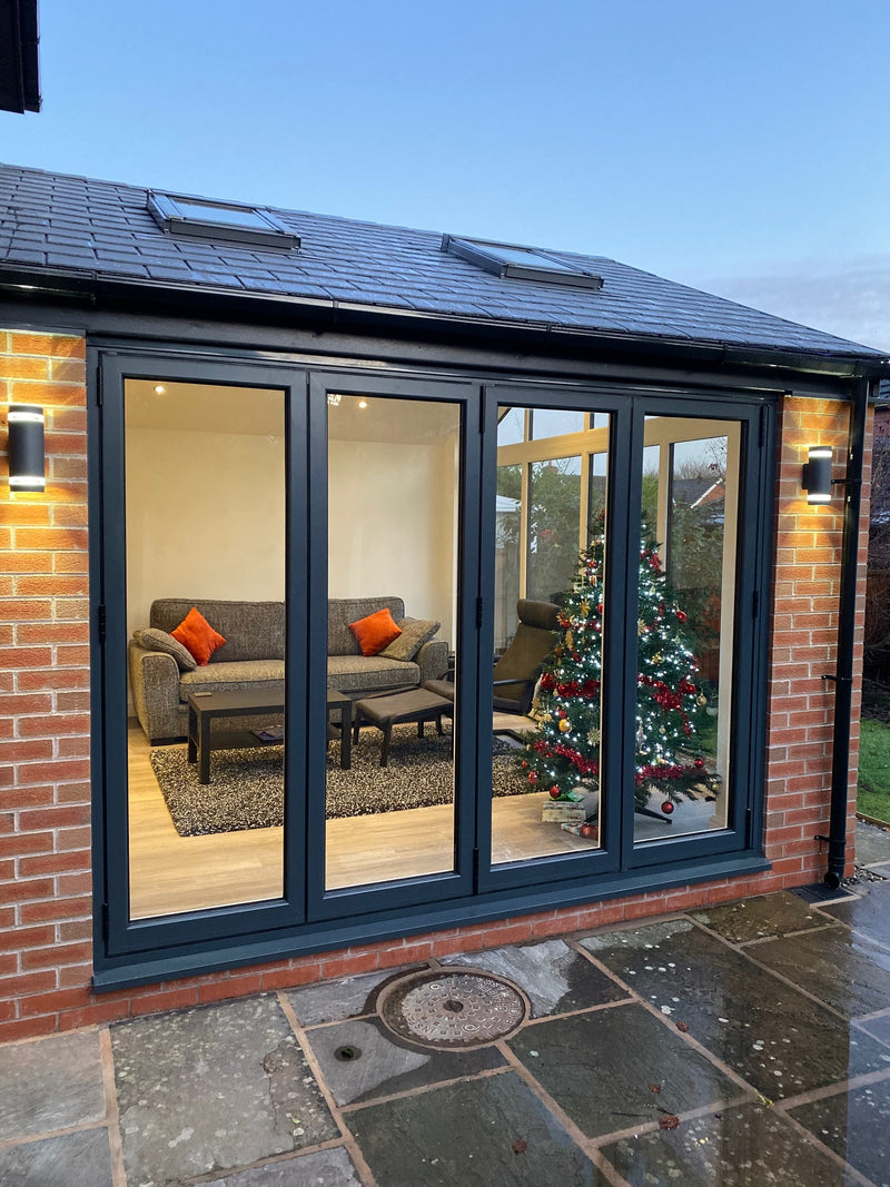 Modern house exterior with large glass door reflecting a living room.