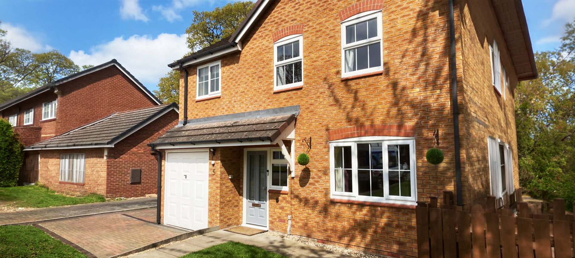 Brick house with white windows and a driveway in a residential area
